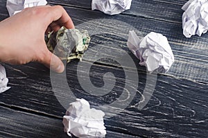 A crumpled dollar on a table next to white paper balls. The process of thinking and finding new business ideas, profitable
