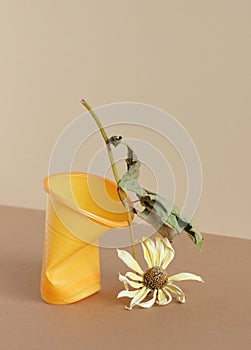 Crumpled empty plastic cup and dry plant on monochrome background, isometric view, plastic waste, waste recycling concept