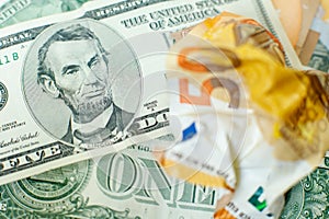 The crumpled 50 euro bill is on on US dollars. Lincoln with a 5 dollar bill grins over crumpled 50 euros. Currency exchange