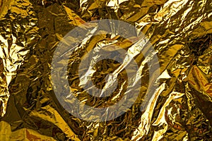 Crumpled foil texture background, close up golden foil