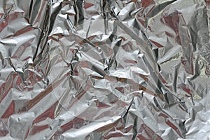 Crumpled foil texture background. Metal paper shit. Silver aluminum surface. Gift wrapping shiny paper. Glitter effect.