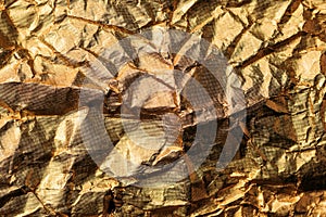 Crumpled gold colored aluminum tin foil texture as background