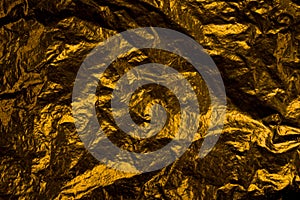 Crumpled gold foil background texture with light reflection