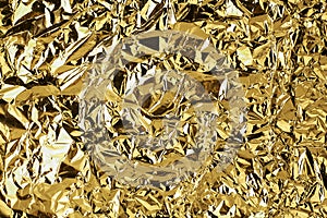 Crumpled golden foil shining texture background, bright shiny gold luxury design, metallic glitter surface