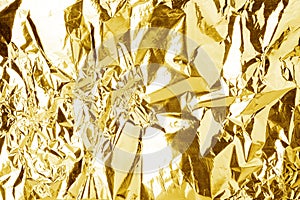 Crumpled golden foil shining texture background, bright shiny gold luxury design, metallic glitter surface