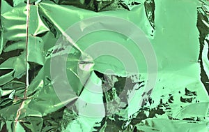 Crumpled green aluminum foil reflective texture background