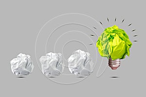 Crumpled green paper light bulb, and white paper balls. Isolated on a grey background. The concept of inspiration, new