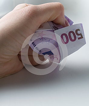 Crushing with a hand a five hundred euros banknote.