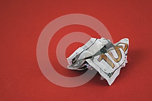 crumpled hundred dollar bill lying on a red background