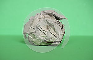 Crumpled paper ball over green