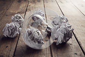 Crumpled paper balls arround light bulb photo
