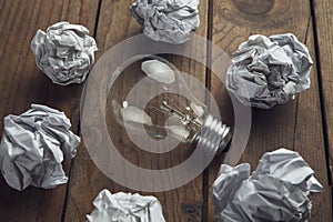 Crumpled paper balls arround light bulb photo