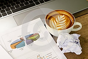 Crumpled paper with coffee cups and labtop computer woth chart for business finance concept backgrounds