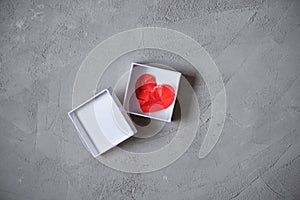 Crumpled paper heart in gift box on the concrete floor.  Broken relationships in bad Valentine`s day. concept.