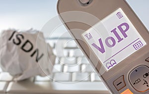 Crumpled paper with the inscription ISDN and modern telephone with VoIP in the display as a sign of the change from ISDN to Voice