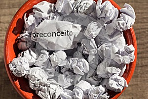 Crumpled paper written preconceito, portuguese word for prejudice, inside the trash can. Paper balls. Concept of old and