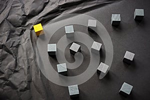 Crumpled paper and a yellow cube as a leader overcomes obstacles.