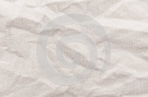 A crumpled piece of fabric with gray waves and folds. Sewing material. White canvas texture background with delicate striped.