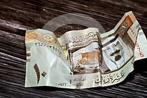 Crumpled Saudi Arabia money of 10 SAR ten riyals isolated on wooden background, wrinkled 10 Saudi Riyals cash bill banknote