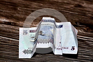 Crumpled Saudi Arabia money of 5 SAR five riyals isolated on wooden background, wrinkled 5 Saudi Riyals cash bill banknote