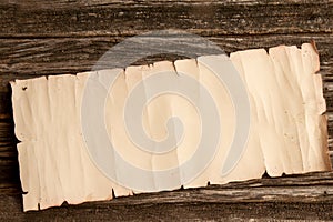 crumpled scroll of paper with place for text on a rough wooden table. Empty background