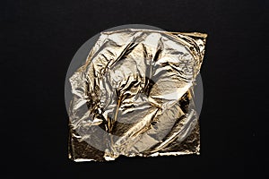 Crumpled sheet of gold on a black background. abstract embossed material