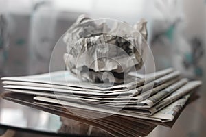 A crumpled sheet of newspaper lies on a stack of fresh newspapers, fake news, corrupt journalism.