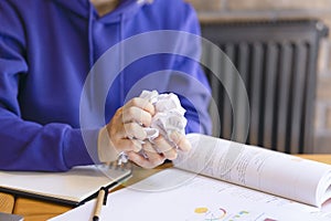 Crumpled sheet of paper in hands close-up, girl in blue sweater.