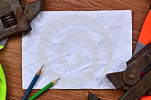 A crumpled sheet of paper with two pencils surrounded by green a