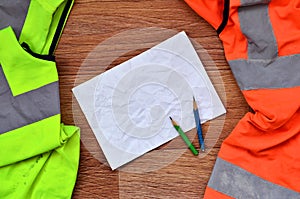 A crumpled sheet of paper with two pencils surrounded by green a