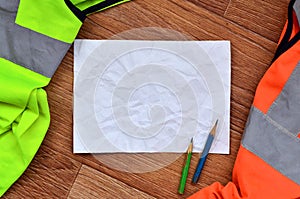 A crumpled sheet of paper with two pencils surrounded by green a