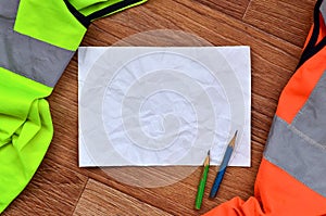 A crumpled sheet of paper with two pencils surrounded by green a