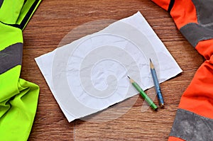 A crumpled sheet of paper with two pencils surrounded by green a