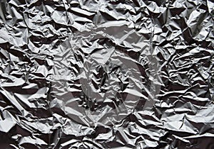 Crumpled silver aluminum foil closeup background texture. Abstract metallic paper holographic pattern