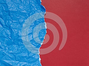 Crumpled and torn blue paper on a background of plain red paper