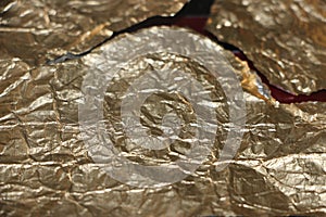 Crumpled and torn golden bronze shiny foil texture background