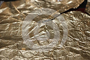 Crumpled and torn golden bronze shiny foil texture background