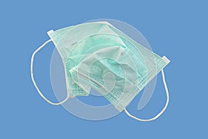 crumpled used surgical face mask isolated on blue background