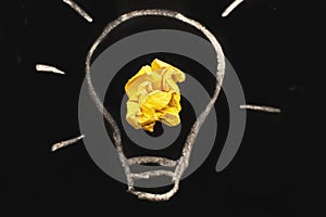 crumpled yelllow paper laightbulb as a concept creative idea on a blackboard background