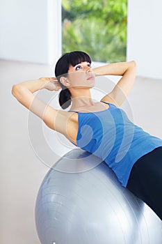 Crunches on the ball. Fit young woman doing sit-ups on an exercise ball.