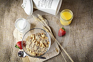 Crunchy breakfast cereal in a bowl with milk on burlap