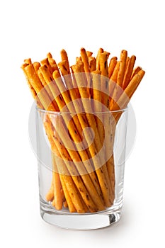 Crunchy thin cheese sticks in glass isolated on white.