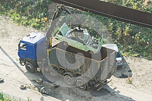 Crushed car being picked up by a grabber. An accident car has been loaded onto a dumptruck by crane. loader crane machine loading