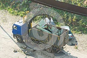 Crushed car being picked up by a grabber. An accident car has been loaded onto a dumptruck by crane. loader crane machine loading