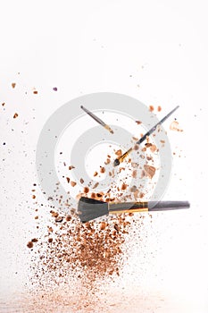 Crushed cosmetic powder with makeup brushes falling