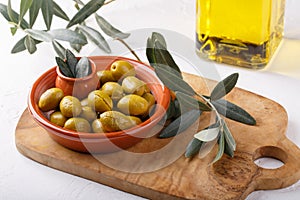 Crushed green olives in bowl on white table. Close-up