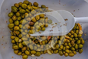 Crushed green olives in a container with a scoop