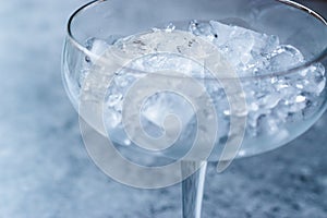 Crushed Ice in Cocktail Glass on Blue Surface.