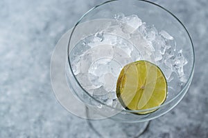 Crushed Ice in Cocktail Glass with Lime on Blue Surface.