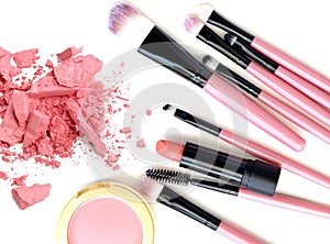 Crushed make up powder and lipstick samples with brushes on white background.